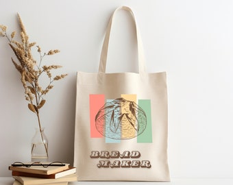 May include: A beige canvas tote bag with a retro-style graphic of a bread loaf on a colorful striped background. The text "BREAD MAKER" is printed in brown letters below the graphic.