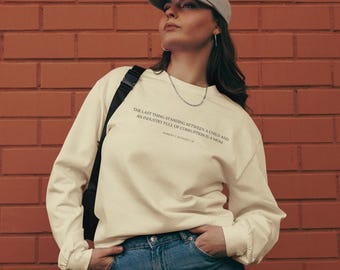 May include: A cream-colored long-sleeved sweatshirt with a quote printed on the front: "The last thing standing between a child and an industry full of corruption is a mom."  The quote is attributed to Robert F. Kennedy Jr.