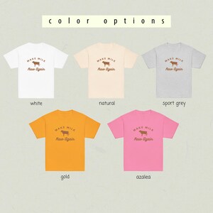 Puede incluir: Cinco camisetas de diferentes colores con el texto "MAKE MILK Raw Again" y un gr&aacute;fico de una vaca. Los colores son blanco, natural, gris deportivo, dorado y azalea.