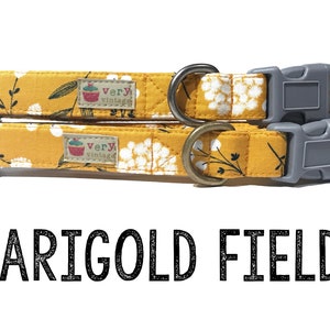 May include: Two yellow dog collars with a white floral pattern and black stems. The collars have a gray buckle and a brass D-ring. The collars have a small label that says "very vintage".