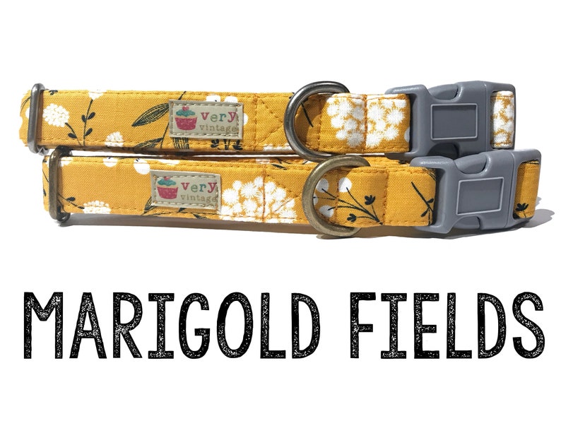 May include: Two yellow dog collars with a white floral pattern and black stems. The collars have a gray buckle and a brass D-ring. The collars have a small label that says "very vintage".