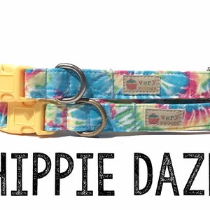 May include: Two tie-dye dog collars with yellow plastic buckles and metal D-rings. The collars are blue, pink, and green with a white background. The collars have a label that says "Very Vintage" with a cupcake logo. The text "Hippie Daze" is below the collars.