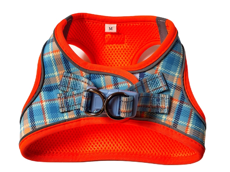 Puede incluir: Arn&eacute;s para perro de cuadros naranja y azul con hebilla azul y plateada. El arn&eacute;s tiene un forro de malla y una etiqueta de talla que dice "M".