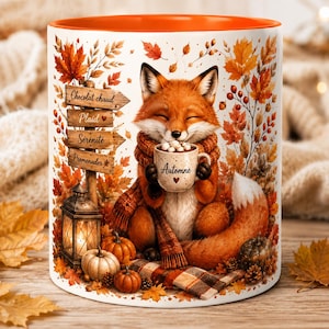 Puede incluir: Una taza de cerámica blanca con interior naranja que muestra un zorro con bufanda sosteniendo una taza con la etiqueta Automne. El diseño incluye hojas de otoño, calabazas, un farol y un letrero de madera con el texto Chocolat chaud, Plaid, Sérénité, Promenades.
