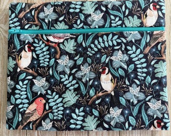 May include: A rectangular quilted pouch featuring a dark navy blue background with a repeating pattern of colorful birds, including goldfinches and a red-breasted bird, nestled among light blue and teal botanical leaves and white flowers with a teal zipper.