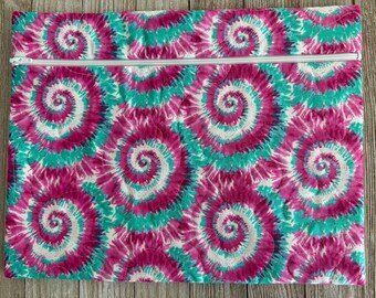 May include: A rectangular, quilted fabric bag with a white zipper closure. The bag features a vibrant tie-dye pattern in shades of pink, teal, and white. The spiral design is evenly distributed across the surface, creating a visually striking effect.