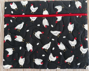 May include: Black quilted fabric pouch with a red zipper. The fabric is patterned with white chickens, red hearts, and white egg shapes. The chickens have red combs and yellow feet.