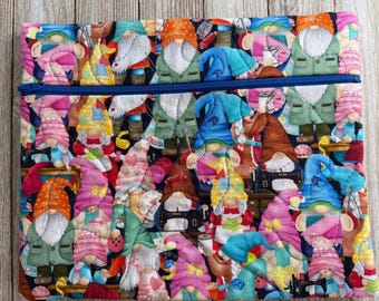 May include: A quilted fabric pouch featuring a colorful pattern of gnomes with white beards, wearing various hats and jackets. The gnomes are surrounded by sewing machines and other sewing supplies. The pouch has a blue zipper.