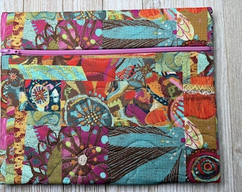 May include: A rectangular quilted fabric pouch featuring a vibrant, multi-colored abstract pattern with shades of teal, magenta, orange, and brown. The pouch includes a horizontal pink zipper closure across the top section of the quilted textile.