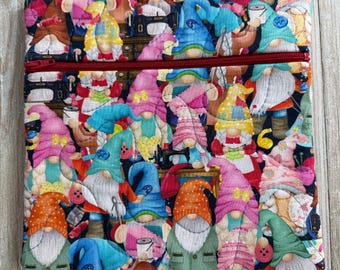 May include: A quilted fabric zippered pouch featuring a repeating pattern of colorful gnomes with white beards and various hats. The gnomes are set against a dark background with sewing-related imagery. The zipper is a deep red color.