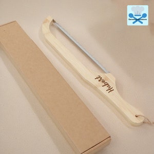 May include: A wooden bread knife with a serrated blade and a handle engraved with the name "Hubert". The knife is packaged in a brown cardboard box.