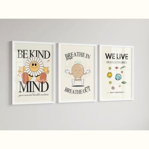 K&ouml;nnte beinhalten: Drei gerahmte Drucke mit motivierenden Botschaften und Illustrationen. Der erste Druck zeigt eine gelbe Blume mit einem l&auml;chelnden Gesicht und dem Text "Sei freundlich zu deinem Geist, deine mentale Gesundheit z&auml;hlt". Der zweite Druck zeigt eine braune Figur, die meditiert, mit dem Text "Einatmen, Ausatmen". Der dritte Druck zeigt einen Cartoon-Planeten mit dem Text "Wir leben auf einem schwimmenden Felsen, &uuml;berdenke es nicht zu viel".