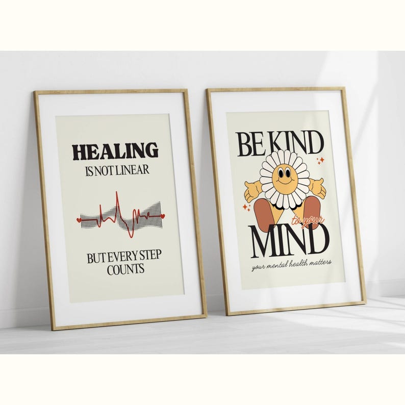 K&ouml;nnte beinhalten: Zwei gerahmte Drucke mit motivierenden Botschaften. Der linke Druck hat eine rote EKG-Linie und den Text "Heilung ist nicht linear, aber jeder Schritt z&auml;hlt". Der rechte Druck hat eine Cartoon-Blume mit einem l&auml;chelnden Gesicht und den Text "Sei nett zu deinem Geist, deine mentale Gesundheit z&auml;hlt".