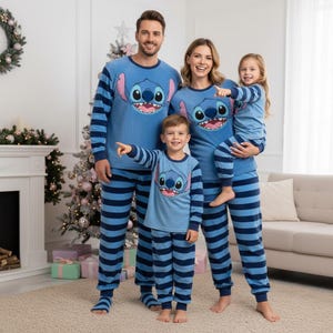 Könnte beinhalten: Eine vierköpfige Familie trägt passende blaue Pyjamas mit einem Stitch-Charakter-Design. Die Pyjamas haben blaue und marinefarbene Streifen auf den Hosen und Ärmeln. Die Oberteile zeigen ein großes Stitch-Gesicht. Die Familie posiert vor einem Weihnachtsbaum.