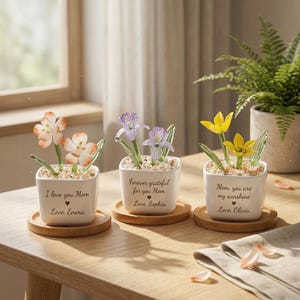 Könnte beinhalten: Ein Set aus drei Keramikbechern mit gesprenkelter, matter Oberfläche. Die Becher sind in Creme-, Hellgrau- und Dunkelgrautönen gehalten. Jeder Becher hat ein schlichtes, minimalistisches Design.