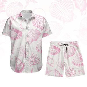 以下が含まれることがあります： ピンクの貝殻とサンゴの模様が施された、白のツーピースセット。半袖シャツと、ウエストに紐が付いたショートパンツのセットです。