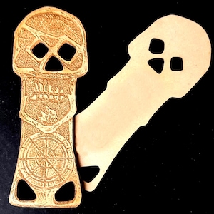 May include: A brown leather skull-shaped key chain with a compass design and a cutout of a skull with three holes. The key chain is shown next to a blank leather cutout of a skull with three holes.