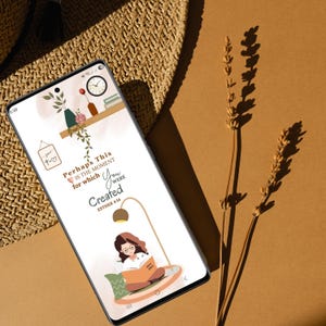 Puede incluir: Un smartphone muestra un fondo de pantalla con el texto "Perhaps This is the moment for which You were Created" y una ilustración de una mujer leyendo. El teléfono está sobre una superficie marrón, junto a un sombrero de paja y plantas secas.