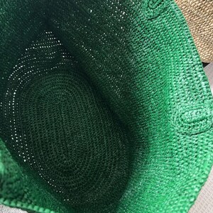 May include: A deep emerald green tote bag constructed from a woven, textured material. The interior of the bag is hollow and shows the consistent, dense crochet-like stitch pattern throughout the base and the side walls of the open container.