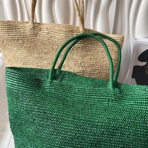 May include: Two large woven tote bags with sturdy handles. One bag is a natural tan color, and the other is a vibrant green. Both bags feature a textured, braided construction with an open top design, providing a spacious interior for carrying items.