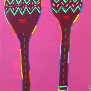 May include: Two wooden spoons painted in a vibrant pink, green, red, yellow, and blue color scheme. The spoons have a zig-zag pattern and a red mouth painted on the top of each spoon.