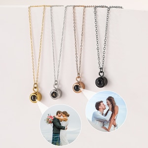 May include: Five silver necklaces with different colored pendants. Each pendant is a small sphere with a hidden image inside. The image is revealed when the sphere is held up to the light.