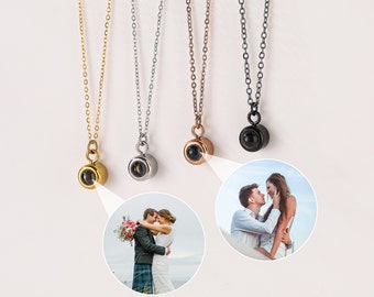 May include: Five silver necklaces with different colored pendants. Each pendant is a small sphere with a hidden image inside. The image is revealed when the sphere is held up to the light.