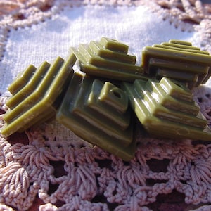 May include: A group of six green plastic pyramid-shaped buttons. The buttons are stacked on top of each other and have a textured surface.