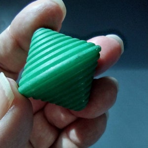 May include: A green, ribbed, cone-shaped toy with a pointed tip.