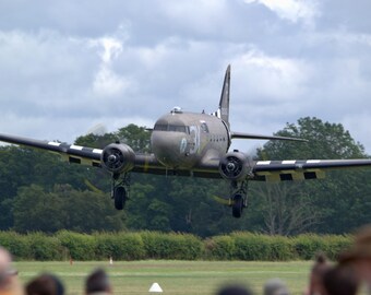 May include: A gray and white military aircraft with black and white markings on the wings and tail. The aircraft is in flight and appears to be taking off.