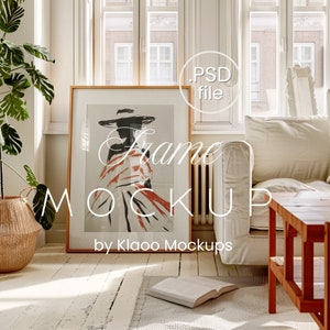 May include: A wooden frame mockup with a white background and a painting of a woman in a hat and a red and white patterned dress. The frame is sitting on a white wooden floor with a white rug and a white couch in the background. The text "Frame Mockup by Klaoo Mockups" is visible in the image.