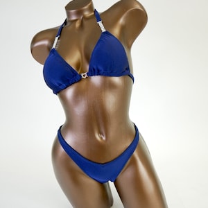 May include: Navy blue bikini with crystal embellishments on the halter top.