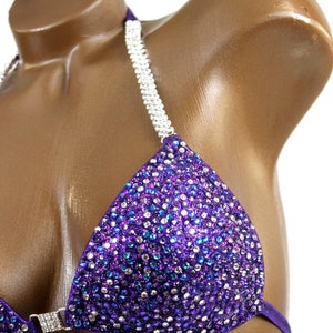 May include: Purple bikini top with silver rhinestones and a halter strap.