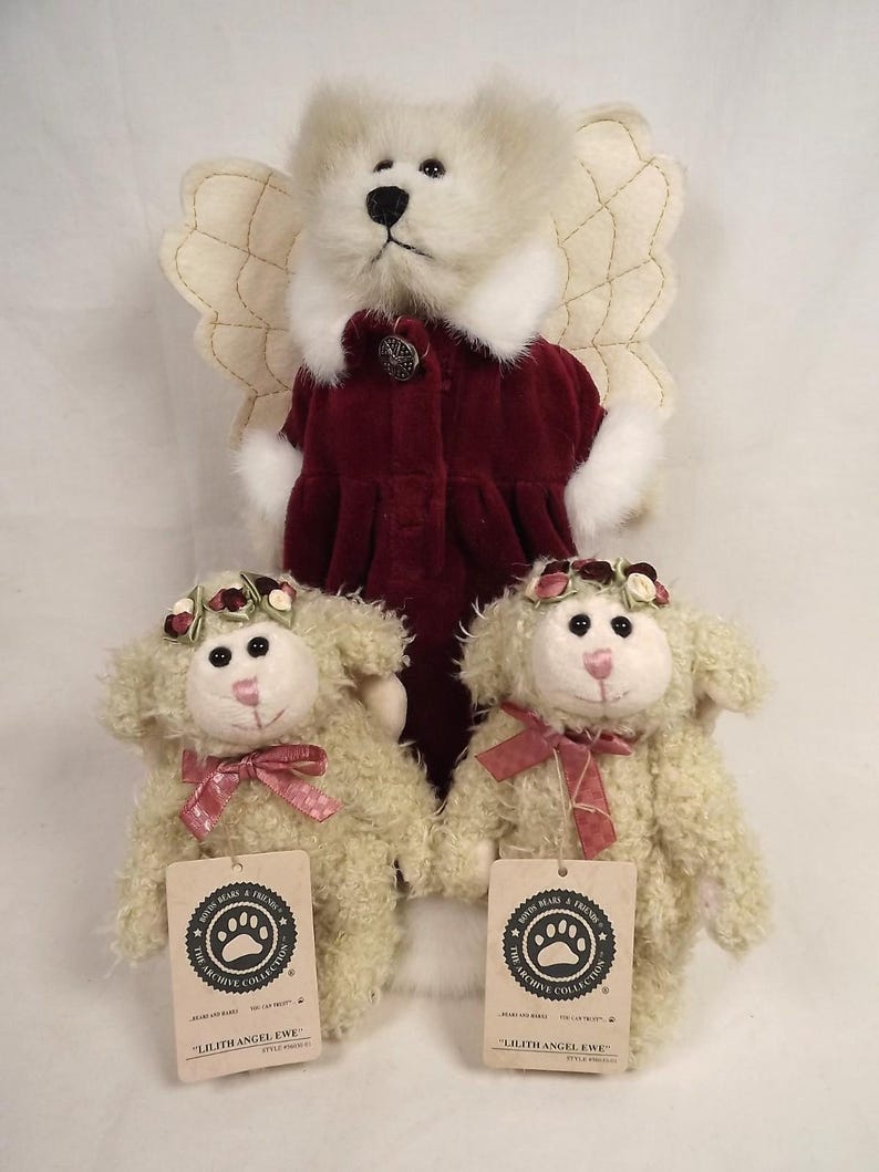 Puede incluir: Una colecci&oacute;n de peluches con un oso &aacute;ngel y dos ovejas Lilith Angel Ewe. El oso &aacute;ngel tiene pelaje color crema, alas y un abrigo burdeos. Las ovejas tienen pelaje color crema, coronas florales y lazos rosas. Cada oveja tiene una etiqueta.