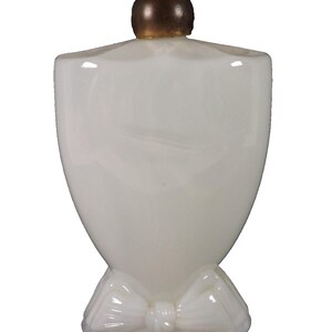 May include: A white glass bottle with a gold top and a white bow at the base. The bottle is shaped like a heart and has a smooth, glossy finish.