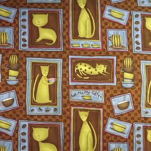 Może przedstawiać: Brązowy materiał z powtarzającym się wzorem kotów i filiżanek do kawy. Koty są żółte i mają różne pozy, niektóre trzymają filiżanki do kawy. Filiżanki do kawy są brązowe i białe z napisem "Java". Tło to brązowy wzór w kratkę.