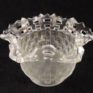 May include: A clear glass bowl with a woven basket design. The bowl has a scalloped edge and is made of frosted glass.
