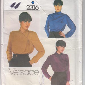 May include: A vintage sewing pattern for a blouse by Versace, Vogue Designer Original pattern number 2316. The pattern shows three different views of the blouse in blue, purple, and brown.