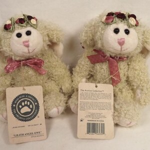 Puede incluir: Dos ovejas de peluche con pelo rizado color crema. Cada una tiene una cara blanca, ojos negros y nariz y boca rosas. Llevan una corona floral y un lazo de cinta rosa. Las etiquetas dicen "Lilith Angel Ewe" y "The Archive Collection."
