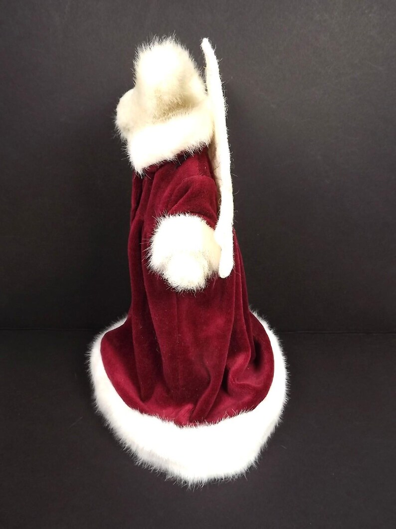 Puede incluir: Un disfraz de Pap&aacute; Noel de terciopelo burdeos con ribete de piel sint&eacute;tica blanca. El disfraz incluye un gorro, pu&ntilde;os y un abrigo largo. El ribete blanco est&aacute; alrededor del gorro, los pu&ntilde;os y la parte inferior del abrigo.