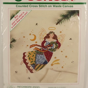 Puede incluir: Un patrón de punto de cruz contado que presenta un ángel de patchwork con un halo, sosteniendo un regalo y volando por el aire. El patrón está en lienzo de desecho blanco e incluye una tabla con acentos de color. El tamaño terminado es de 23 cm por 23 cm.