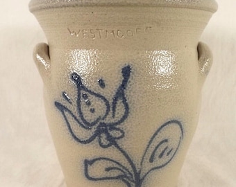 Puede incluir: Un tarro de cerámica blanco con esmalte azul y un diseño floral. El tarro tiene dos asas y las palabras "Westmoore" están estampadas en el lateral.