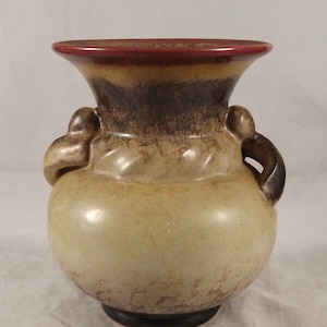 Könnte beinhalten: Eine Keramikvase mit zwei Henkeln, einem runden Korpus und einer ausgestellten Oberseite. Die Vase ist mit einer braunen, braunen und roten Glasur verziert.