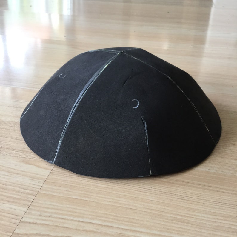 May include: A black foam dome with white lines drawn on the surface. The dome has two small holes on the top.