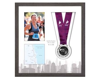 Puede incluir: Presentación enmarcada con una foto de una corredora de maratón, un mapa y una medalla. La medalla tiene una cinta morada y la palabra "Chicago". La foto muestra a una mujer corriendo con el número 181 en su camiseta. El marco es gris.