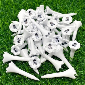 May include: A pile of white golf tees with black skull and crossbones designs.