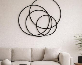 Pode incluir: Arte de parede em metal preto com círculos sobrepostos de vários tamanhos. O design geométrico moderno é montado em uma parede branca texturizada. A obra de arte é um elemento decorativo para espaços interiores.