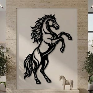 Peut inclure: Une décoration murale en métal noir représentant un cheval cabré avec une crinière et une queue fluides, fixée sur un mur clair au-dessus d'une cheminée. Une petite figurine de cheval clair est posée sur la cheminée sous l'œuvre.