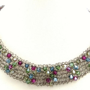 May include: A silver wire necklace with multi-coloured crystal beads. The beads are in shades of pink, blue, and green.