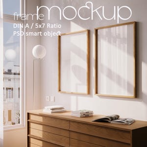 Op de afbeelding: Twee houten ingelijste kunstmockups met witte achtergronden hangen aan een witte muur. De frames zijn rechthoekig met een lichtbruine houten afwerking. De tekst "frame mockup" staat bovenaan de afbeelding. Een houten dressoir met boeken en een tijdschrift staat eronder.